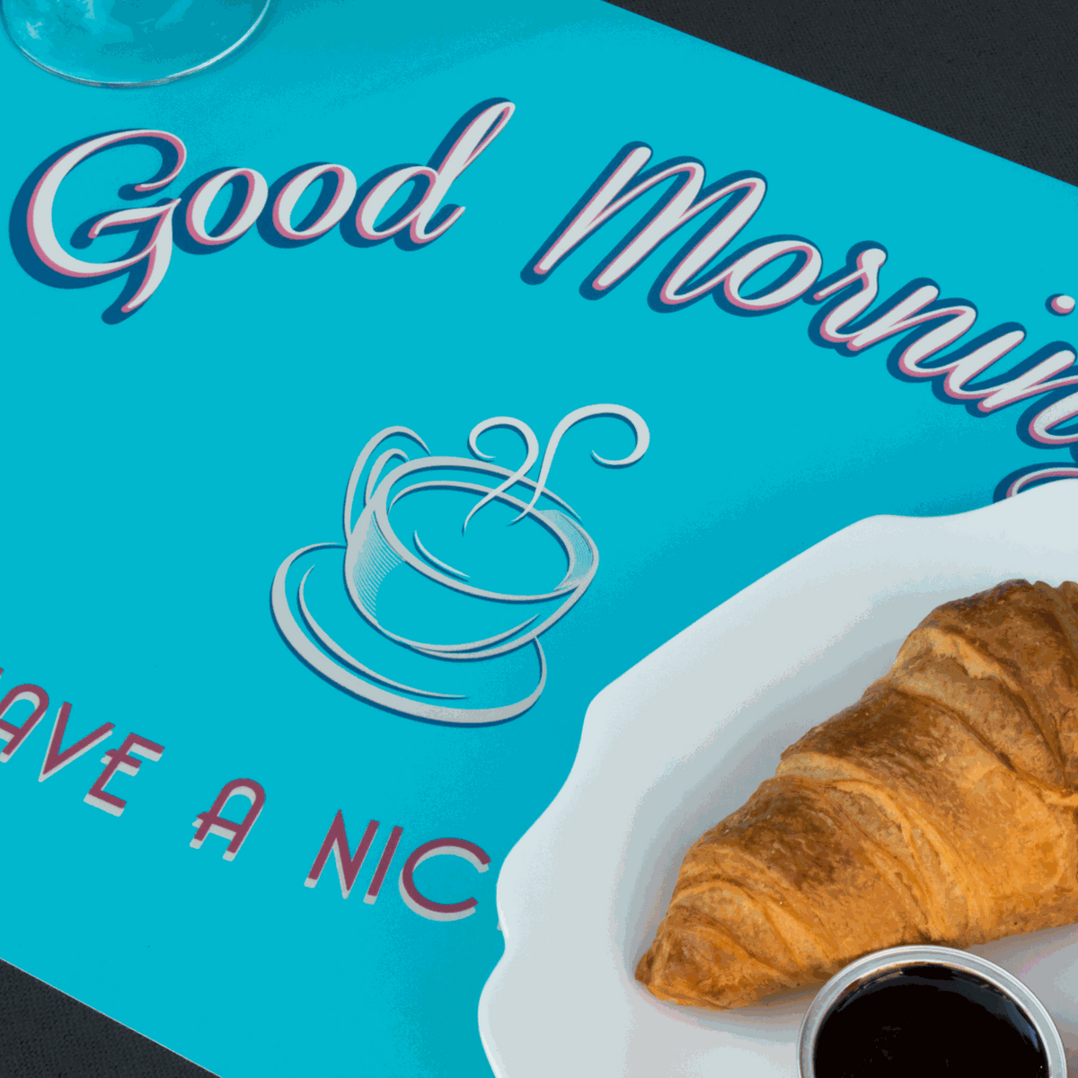 Tischset Food aus Kunststoff in Türkis mit Kaffee- und Croissant-Motiv sowie Schriftzug „Good Morning“