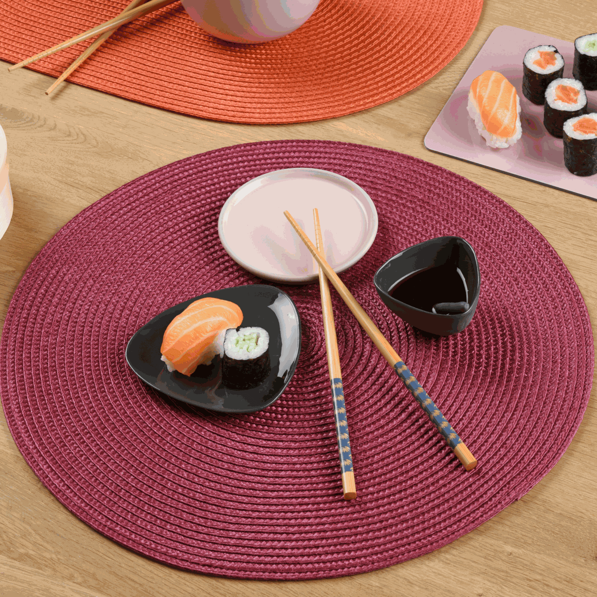 Tischset gewebt, rund in Bordeauxrot mit strukturierter Kunststoffoberfläche, dekoriert mit Sushi und Essstäbchen