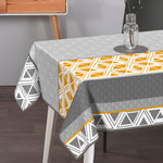 Textile Tischdecke aus Textil in Grau und Weiß mit geometrischem Rauten- und Dreieckmuster, orangefarbenen Akzenten und Borte
